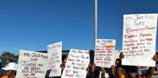 Nelson Mandela Bay Mourns Tragic Loss of Teen Girls in KwaNobuhle Community members mourn two teen girls in KwaNobuhle with candles and flowers at a memorial site.